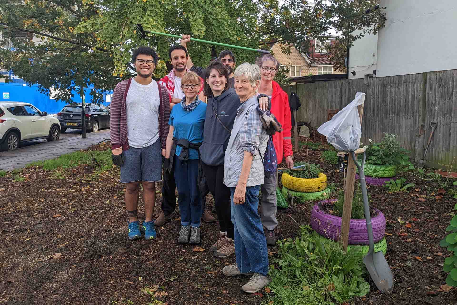 A group of people standing in a green space garden.