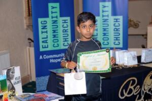 A young boy holding a certificate and a bag