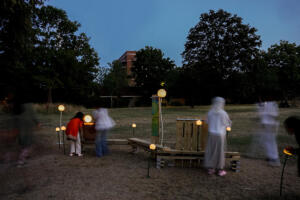 People standing by an illuminated outdoor seating in park in Dean Gardens, West Ealing