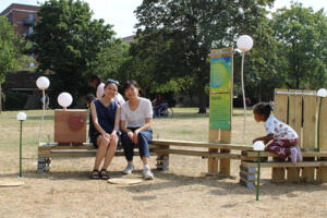 Two woman sitting by outdoor seating furniture in park in Dean Gardens, West Ealing